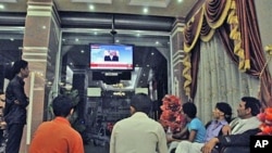 Yemenis watch a TV broadcasting an audio broadcast of Yemeni President Ali Abdullah Saleh, in a hotel in Taiz, Yemen, Friday, June 3, 2011