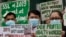 FILE - Health workers wearing protective masks hold signs during a rally outside a hospital in metropolitan Manila, Philippines, Feb. 7, 2020, demanding the government ensure their safety and raise their pay amid to the coronavirus threat.