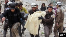 Des membres de la défense civile syrienne, connus sous le nom de Casques blancs, retirent une victime des décombres d'un bâtiment détruit suite à une attaque aérienne à Idlib, Syrie, 15 mars 2017