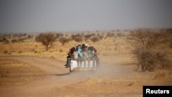 FILE - Migrants cross the Sahara Desert into Libya on the back of a pickup truck outside Agadez, Niger, May 9, 2016.