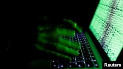 FILE - A man types on a computer keyboard in front of displayed cyber code in this illustration picture.