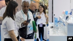 资料照片: 2023年11月4日广州进出口商品交易会上，参展商在推广保健设备的展位上接待外国参观者。