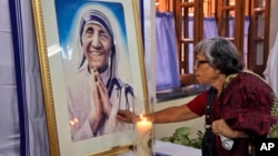 An Indian Catholic woman offers prayers as she touches a portrait of Mother Teresa on her 17th death anniversary at the Missionaries of Charity in Kolkata, India, Sept. 5, 2014.