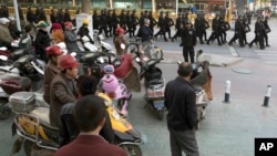FILE - Residents watch a convoy of security personnel in a show of force through central Kashgar in western China's Xinjiang region, Nov. 5, 2017.