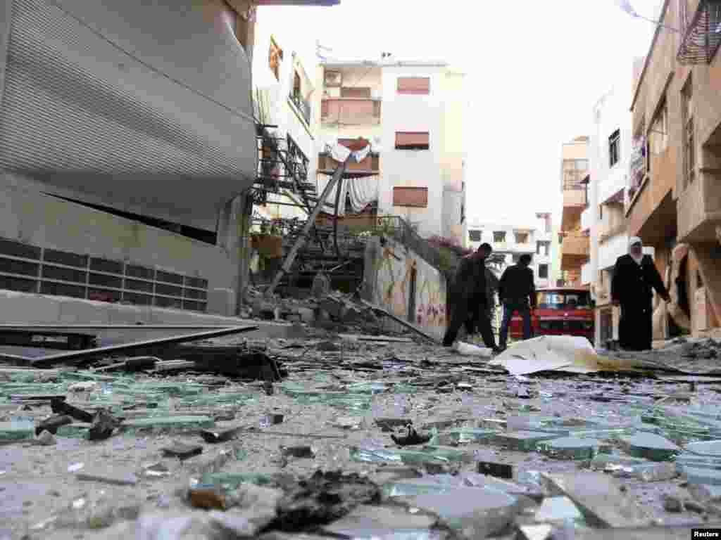 Residents walk near debris from damaged buildings after shelling by forces loyal to Syria's President Bashar al-Assad at Daria near Damascus, Syria, November 26, 2012.