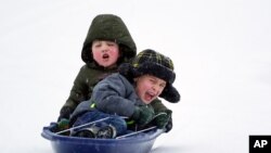 Two boys sled down an icy street on Feb. 15, 2021, in Nolensville, Tenn. Much of Tennessee was hit with a winter storm that brought freezing rain, snow, sleet and freezing temperatures.