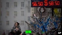 People walk past a sign advertising currency exchange rates in Moscow, Russia, Dec. 12, 2014.