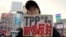 FILE - A protester holds a sign reading "We oppose Japan to join the TPP negotiation talks" during a rally against the Trans-Pacific Partnership in Tokyo. 