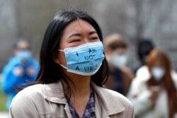 A demonstrator wearing a mask saying "I am not a virus" listens to a speech at a rally against Asian hate crimes, March 27, 2021 at Chicago's Grant Park.