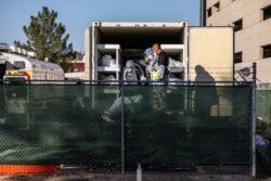 El Paso County detention inmates, Sheriff officers and morgue staff help move bodies to refrigerated trailers deployed during a surge of COVID-19 deaths, outside the Medical Examiner's Office in El Paso, Texas, Nov. 14, 2020.