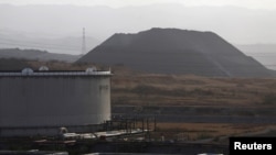 En el fondo de la imagen aparece un montículo de coque junto a un tanque de petróleo en el complejo industrial José Antonio Anzoátegui de PDVSA en el estado de Anzoátegui el 15 de abril de 2015. Archivo.