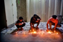 People light candles at the site of a bombing in Wahailat market in Sadr City, Iraq, July. 19, 2021.