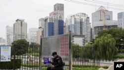 FILE - A security guard mans his post across from the central business district in Beijing, China, Oct. 5, 2021.