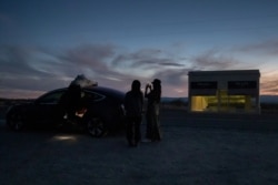 Richard He, Yao Li and Nora Liu, students from China studying at Rice University, photograph the Prada Marfa art installation in Valentine, Texas, Nov. 2, 2020.