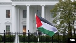 হোয়াইট হাউসের বাইরে ফিলিস্তিনিপন্থী বিক্ষোভকারীরা একটি ফিলিস্তিনি পতাকা নাড়ছে। ২ এপ্রিল, ২০২৪। 