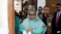 FILE - Sheikh Hasina checks her watch as she waits for the official opening time to cast her vote in Dhaka, Bangladesh, Jan. 7, 2024.