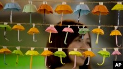 A woman poses for a photo with the paper fold umbrellas at the occupied area in Causeway Bay, a shopping district of Hong Kong, Oct. 21, 2014. 