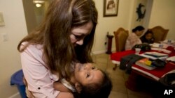 FILE - Immigration activist Nora Sandigo hugs Britzaida, 4, one of the many children of immigrant parents that have signed a power of attorney over to Sandigo that enables her to care in the event they are suddenly detained, in Miami, FL., Jan. 10, 2018. 
