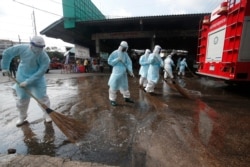 Workers clean the road outside shrimp market in Samut Sakhon, Bangkok, Jan. 25, 2021, as Thailand registered a new daily high of over 900 cases of the coronavirus at the province near the capital Bangkok, where a major outbreak occurred in December.