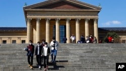 Personas con máscaras caminan por las escaleras del Museo de Arte de Filadelfia, en Filadelfia, EE.UU.