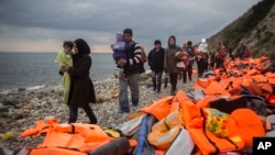 Refugees and migrants walk along a beach after crossing a part of the Aegean on a dinghy, from Turkey to the Greek island of Lesbos, Dec. 12, 2015. 