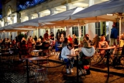 People sit at tables in Covent Garden, London, Dec. 12, 2020. Health Secretary Matt Hancock says infections are starting to rise in some areas after falling during a four-week national lockdown in England that ended Dec. 2.