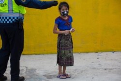 A child wearing a protective face mask, stands in line to receive a free meal in the Peronia neighborhood of Villa Nueva, Guatemala, July 24, 2020.