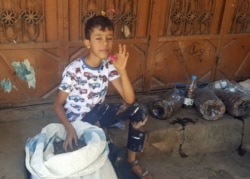 A boy holds up a pink mature locust. (N. Shaker/VOA)