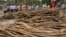 FILE - Cambodian villagers are pictured next to piles of timber in Koh Kong province, 300 kilometers southwest of Phnom Penh, in May 2012. The Cambodian government has long been battling the problem of illegal logging. 