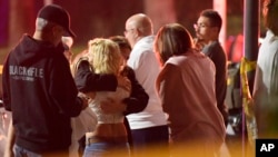People comfort each other as they stand near the scene, Nov. 8, 2018, in Thousand Oaks, Calif. where a gunman opened fire Wednesday inside a country dance bar crowded with hundreds of people.