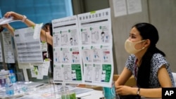 An official sits behind a plastic barrier inside a COVID-19 testing site within the Main Press Center at the 2020 Summer Olympics, Thursday, July 22, 2021, in Tokyo, Japan. 