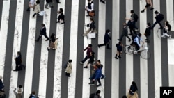 FILE - People walk along a pedestrian crossing at Ginza shopping street in Tokyo, on March 31, 2023, in Tokyo. 