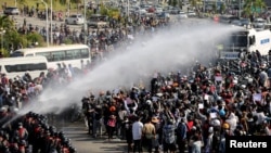 Police fire a water cannon at protesters demonstrating against the coup and demanding the release of elected leader Aung San Suu Kyi, in Naypyitaw, Myanmar, Feb. 8, 2021. 