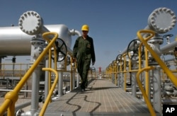 FILE - Oil technician Majid Afshari makes his way to the oil separator facilities in Iran's Azadegan oil field southwest of Tehran, April 15, 2008.