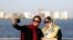 FILE - Iranians take a selfie at the Persian Gulf Martyrs lake, west of Tehran, July 7, 2019. Some daring women in Iran's capital have been taking off their mandatory headscarves, or hijabs, in public, risking arrest.