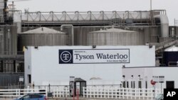 FILE - Vehicles sit in a near empty parking lot outside the Tyson Foods plant in Waterloo, Iowa, May 1, 2020. 