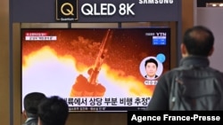 People watch a television screen showing a news broadcast with file footage of a North Korean missile test, at a railway station in Seoul on Jan. 25, 2022.