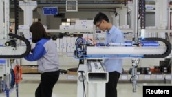 FILE - Workers test industrial robots at a factory of Topstar Technology during a government-organised tour to the Guangdong-Hong Kong-Macao Greater Bay Area, in Dongguan, Guangdong province, China, March 1, 2019. 