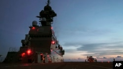 FILE - Aircraft maintenance engineers prepare to stow away an SH-60K helicopter on the flight deck aboard Japan's Maritime Self-Defense Force helicopter carrier JS Izumo (DDH-183) on June 26, 2019.