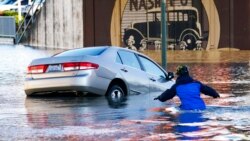 FILE - Kenneth Warner races to help rescue the driver of a car that went into the flooded Nooksack River, Nov. 16, 2021, in Ferndale, Wash. It's been a weird winter in the United States. The Pacific Northwest has received record rainfall while the Rockies still haven't seen their first significant snowfall.
