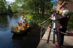 FILE - Reinier Sijpkens performs classical music on his music boat for elderly people confined to their nursing home because of the coronavirus, in Heemstede, Netherlands, April 27, 2020.