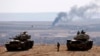 Turkish army tanks are seen on the Turkish side of the border as smoke rises from the Syrian town of Kobani Oct. 8, 2014.
