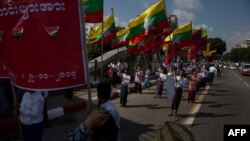 Men carry Myanmar national flags as they march in a show of support for the country's military and civil servants, in Yangon, Myanmar, Oct. 29, 2017.