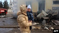 ২০২৪ সালের ২৫ ফেব্রুয়ারি ইউক্রেনে ডনেটস্ক অঞ্চলে রাশিয়ার ক্ষেপণাস্ত্র হামলায় বিধ্বস্ত রেলস্টেশনের পাশ দিয়ে স্থানীয় এক বাসিন্দা তার সন্তান নিয়ে হেঁটে যাচ্ছেন।