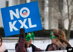 FILE - Two women wearing sunglasses with a tree design join other opponents of the Keystone XL pipeline to celebrate President Barack Obama's veto of legislation pertaining to the project outside the White House in Washington, Feb. 24, 2015.