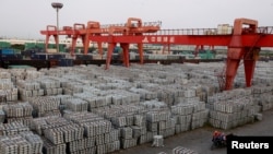 FILE - Workers ride through an aluminum ingots depot in Wuxi, Jiangsu province, China, Sept. 26, 2012. President Donald Trump imposed tariffs on aluminum and steel in March of 2018, with the goal of boosting U.S. production.