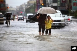 FILE - Local residents walk through floodwaters from passing Tropical Storm.