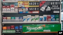 FILE - Packs of cigarettes are offered for sale at a convenience store in Helena, Montana, May 18, 2017. Tobacco companies were ordered to include new statements on cigarette packages by November 2018.