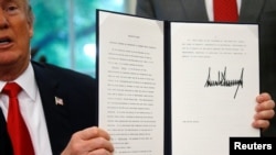 U.S. President Donald Trump displays an executive order on immigration policy after signing it in the Oval Office at the White House in Washington, June 20, 2018.