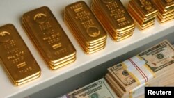 FILE - Gold bars and U.S. dollar bills.